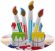 four paintbrushes are sitting in different colors on a tray with watercolors