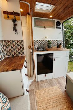 the interior of a small camper with wood flooring and white cabinets, including an oven