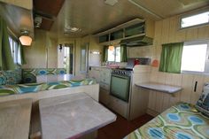 a kitchen and living room inside of a mobile home with green curtains on the windows