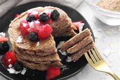 a stack of pancakes topped with berries and coconut