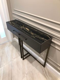 a black marble top console table with two drawers on one side and an open drawer on the other