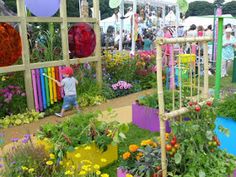 an outdoor garden with lots of colorful flowers and plants in the center, surrounded by people