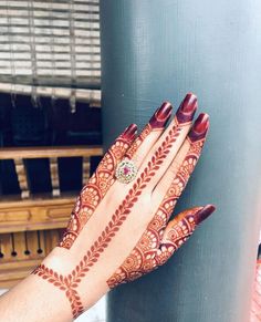 a woman's hand with henna on it and her hands holding onto a pole