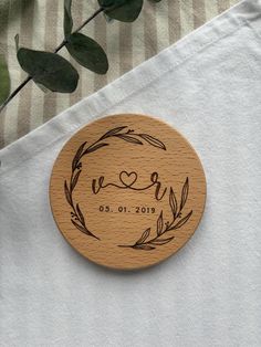 a wooden coaster with the word love engraved on it next to some leaves and a potted plant