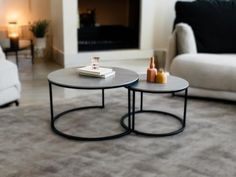 two tables sitting on top of a carpeted floor in front of a white couch