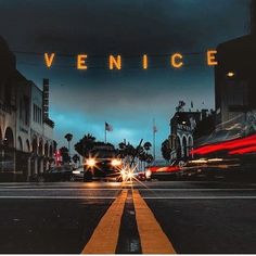 a city street at night with the word venice lit up