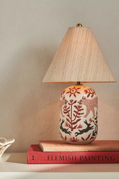 a lamp sitting on top of a table next to two books and a lamp shade