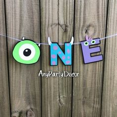 an eye themed banner hanging on a wooden fence with the word ne spelled in purple and green