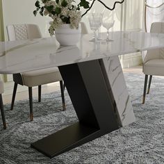 a marble dining table with white chairs and flowers in vase on the top, next to an area rug