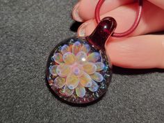 a close up of a person's hand holding a glass pendant