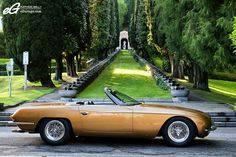 an orange sports car parked in front of some trees