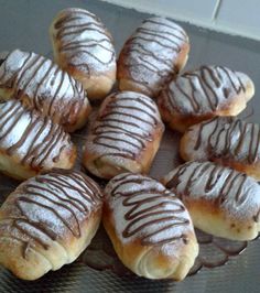 a bunch of doughnuts with chocolate drizzled on them sitting on a glass plate