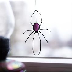 a spider mobile hanging from a window sill in front of a blurry background