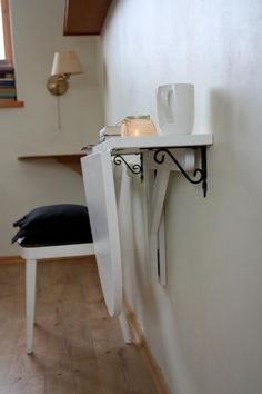 a white table with a candle on it next to a chair and shelf in a room