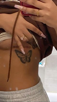 a woman with tattoos on her stomach and hand holding a cell phone to her side