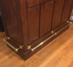 a wooden cabinet with brass handles on the top and bottom, sitting on a hard wood floor