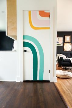 an open door in a living room with wood flooring and artwork on the wall