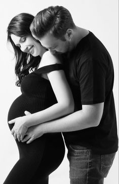 a pregnant couple cuddles in black and white