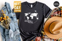 a t - shirt with the words adventure awaits on it next to a hat and flowers