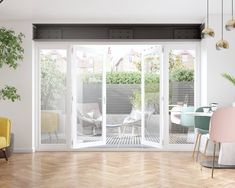 an open living room with sliding glass doors and chairs in the corner, next to a potted plant