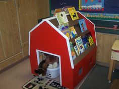 a child's play house made out of cardboard with books on the shelves and stuffed animals inside