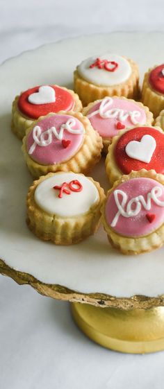 small cookies decorated with hearts and love on a cake plate for valentine's day