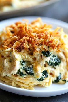 a white plate topped with pasta covered in cheese and spinach