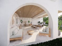 a living room with white couches and tables in front of an arched doorway that leads to the outside patio