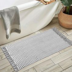 a bath tub sitting next to a rug on top of a wooden floor in a bathroom