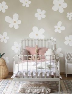 a white bed sitting in a bedroom next to a wall with flower decals on it