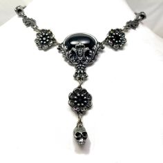 "Black cabochon stone with leaves and skulls with Black crystal eyes Flowers with Black crystal centers & Vitrail crystal details around Adjustable length 14-18\" Lead free pewter Always ethically sourced bones. Nothing has ever been harmed for the purpose of our jewelry. All pieces are made-to-order despite the \"in stock\" number in the listing. Time frame varies from piece to piece so please message us if you need something by a certain date and we will do our best. A portion of our profi Black Skull Necklace With Oxidized Finish, Black Oxidized Skull Necklace, Gothic Oval Metal Jewelry, Nickel Free Black Skull Necklace, Black Nickel Free Skull Necklace, Black Nickel-free Skull Necklace, Gothic Silver Oval Necklace, Nickel-free Gunmetal Gothic Jewelry, Vintage Black Skull Jewelry