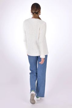 the back view of a woman wearing a white sweater and jeans