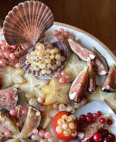 an assortment of fruits and vegetables on a plate with seashells, starfish