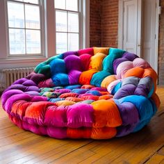 a multicolored bean bag chair sitting on top of a wooden floor next to a window