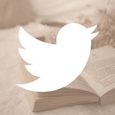 an open book sitting on top of a bed next to a white dove logo with flowers