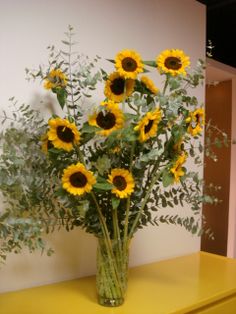 a vase full of sunflowers sitting on a yellow table