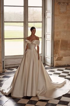 a woman in a wedding dress standing on a checkered floor with an open door