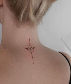 a woman's back neck with a small flower tattoo on the left side of her neck