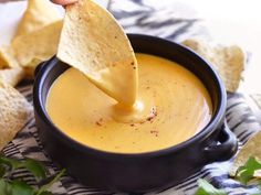 a tortilla chip being dipped into a bowl of quesadilla dip