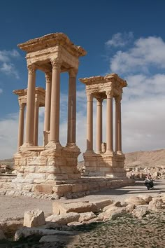 an ancient structure in the desert with people walking around it