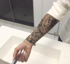 a person with a rose tattoo on their arm holding a knife in front of a sink