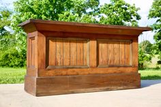 a wooden bench sitting on top of a cement ground next to a lush green field