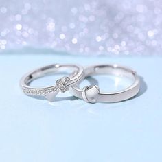 two white gold wedding rings with diamond accents on a light blue background, close up