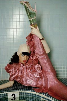 a woman laying on top of a bath tub in a pink dress and high heels