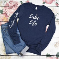 Perfect for a gift or for yourself to personalize by adding your favorite lake name to the sleeve.  Introducing our lightweight and stylish Lake Life Long Sleeve T-Shirt, crafted on the comfortable and premium Bella Canvas 3501 in the Heather Navy color. This is a unisex design so size down for a fitted look. Very soft and comfortable. Embrace the tranquil beauty of lake life with this soft and breathable long sleeve tee, perfect for those cool mornings and evenings by the water. Made from a blend of high-quality materials, this shirt offers the perfect balance of comfort and style, ensuring you stay cozy without feeling weighed down. Featuring a trendy lake-inspired design, whether you're lounging on the dock, enjoying a leisurely boat ride, or simply exploring the shoreline, this tee add Long Sleeve T-shirt With Lettering, Spring Long Sleeve Tops With Lettering, Casual Custom Text T-shirt For Fall, Fall Casual T-shirt With Custom Text, Casual Fall T-shirt With Custom Text, Casual Long Sleeve Tops With Custom Text, Blue Long Sleeve Top With Name Print, Customizable Long Sleeve Cotton T-shirt, Custom Print Long Sleeve T-shirt For Spring