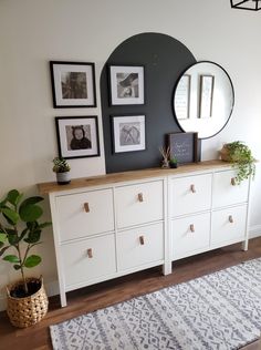 a white dresser sitting next to a wall with pictures on it