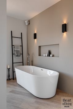 a white bath tub sitting on top of a hard wood floor next to a ladder