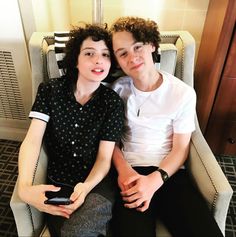 two people sitting on a chair with their arms around each other