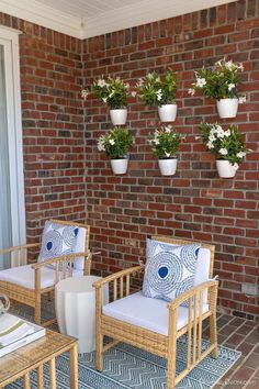 three chairs and two tables on a patio with potted plants hanging from the wall