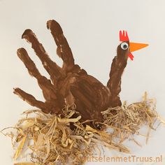 a hand with a fake turkey head sticking out of it's center surrounded by hay